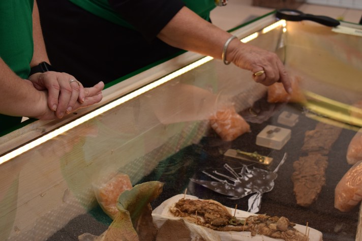 A hand points out the sword among the Anglo-Saxon objects in the coffin display case.