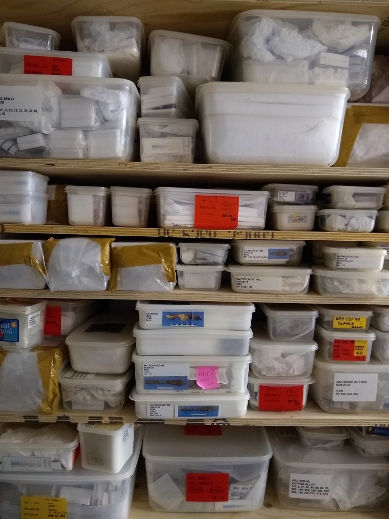 Shelves full of clear tupperware boxes of different sizes, with different colour labels on them. 