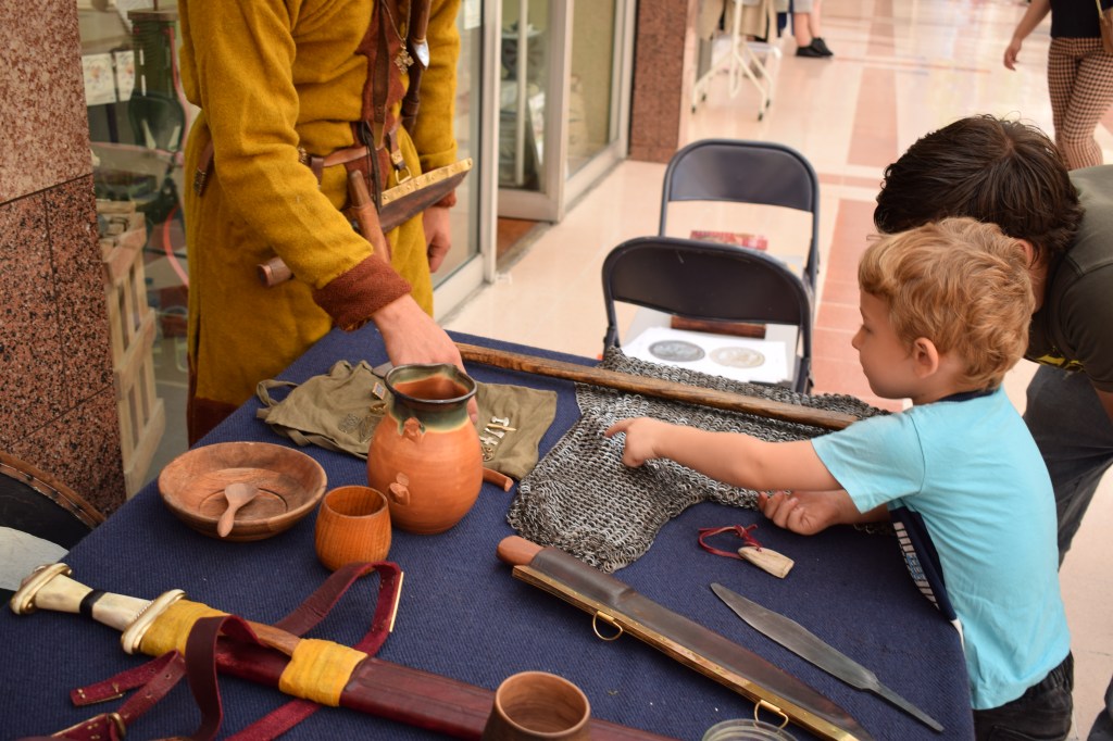 A young boy points out a detail on replica Anglo-Saxon chainmail